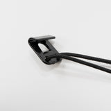 Schwarzer Klammerclip mit zwei schwarzen Schnüren auf weißem Hintergrund.