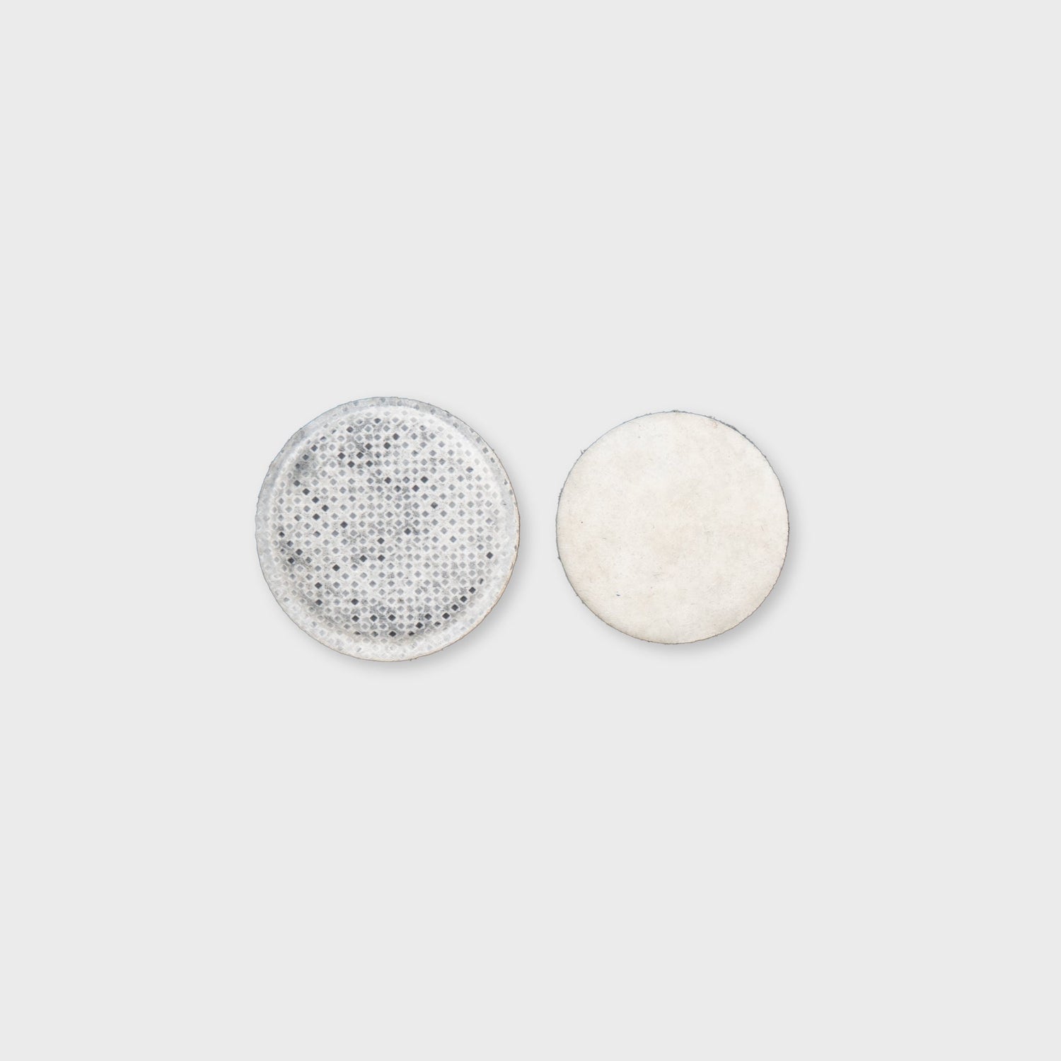 Zwei runde, flache Filter: einer mit perforierter Oberfläche und einer glatten, hellen Seite. Ideal für verschiedene Anwendungen.