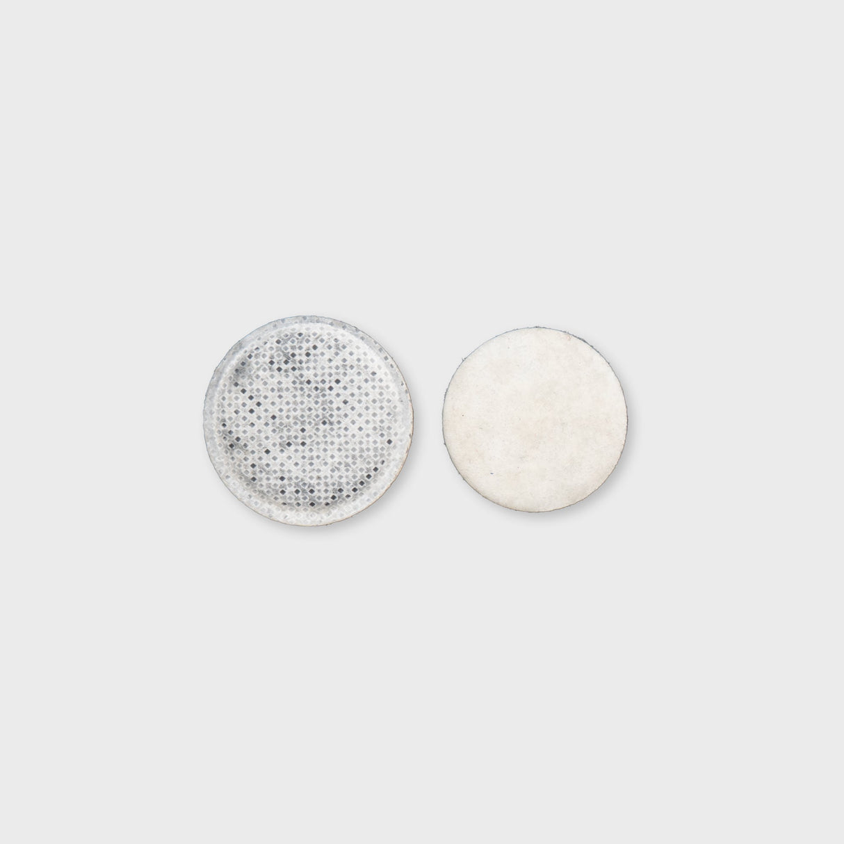 Zwei runde, flache Filter: einer mit perforierter Oberfläche und einer glatten, hellen Seite. Ideal für verschiedene Anwendungen.