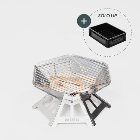 Robuster Edelstahl-Grill mit Holzkohleschicht und Grillrost, daneben schwarzer Aufbewahrungskasten.