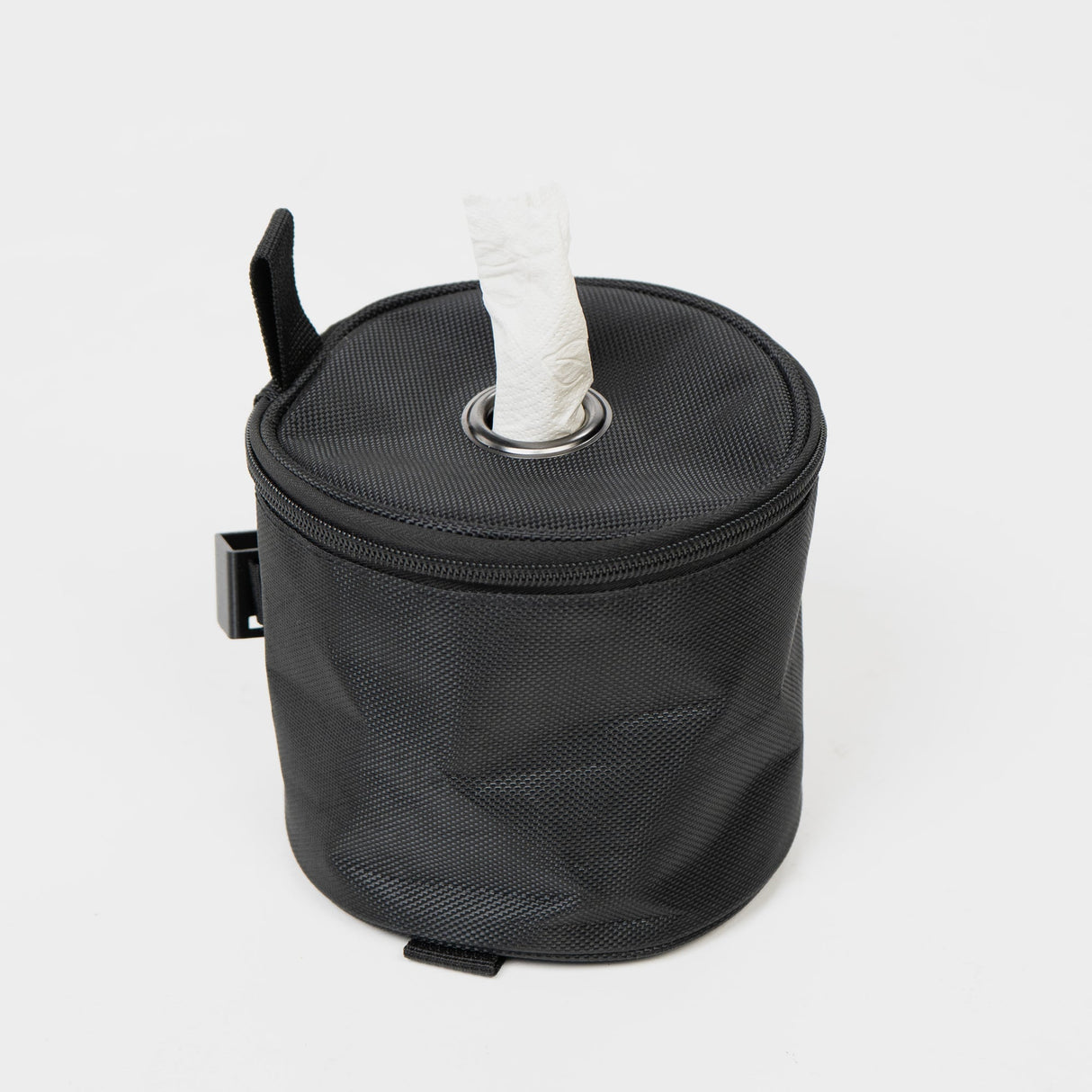 Schwarze, runde Tasche mit offenem Deckel und Papiertaschentuch, ideal für unterwegs und praktische Aufbewahrung.