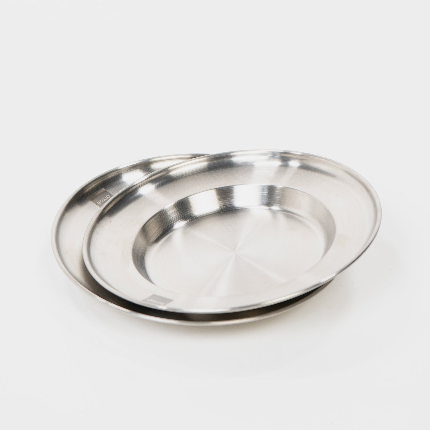 Zwei ineinander liegende Edelstahlplatten mit glänzender Oberfläche auf weißem Hintergrund.