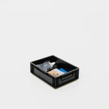 Schwarze Aufbewahrungsbox mit Reinigungsutensilien wie Sprühflasche, Tuch und Putzmaterialien.