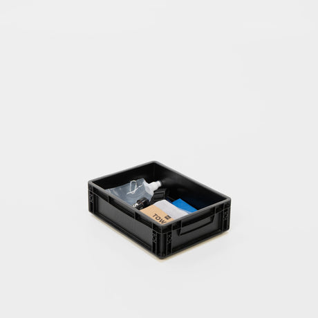 Schwarze Aufbewahrungsbox mit Reinigungsutensilien wie Sprühflasche, Tuch und Putzmaterialien.