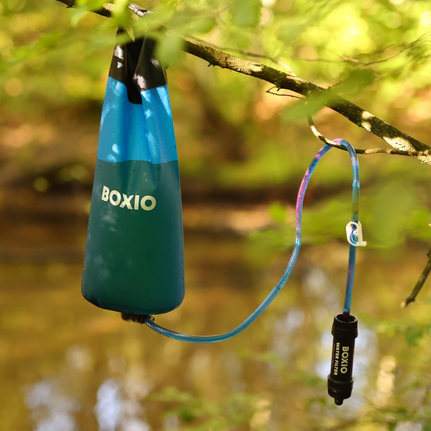 Hängender Wasserfilter von BOXIO an einem Ast, bereit zur Nutzung in der Natur.