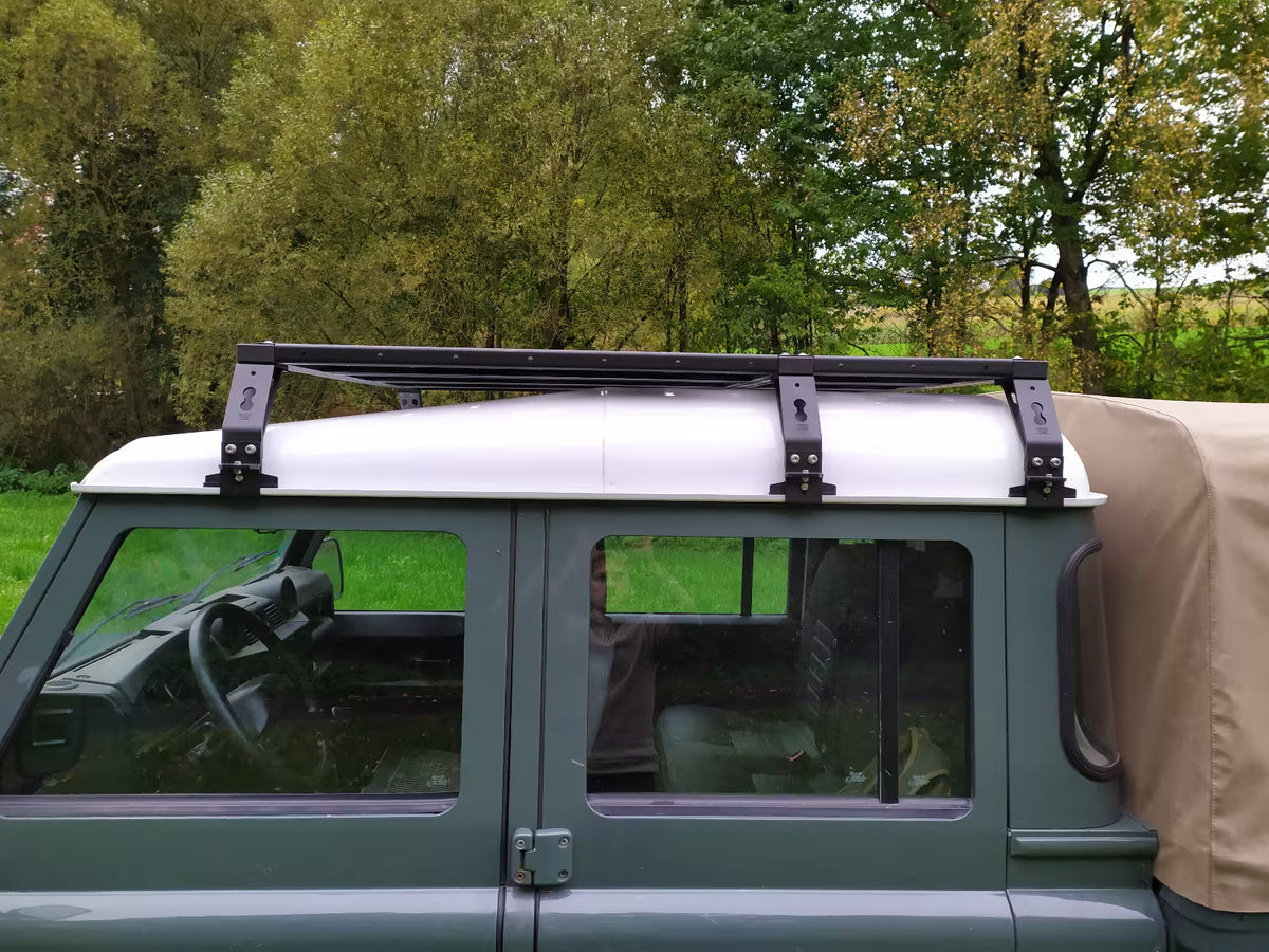 Rolling Space Dachträger, seitlich auf einem grünen Defender mit beigem Planenaufbau